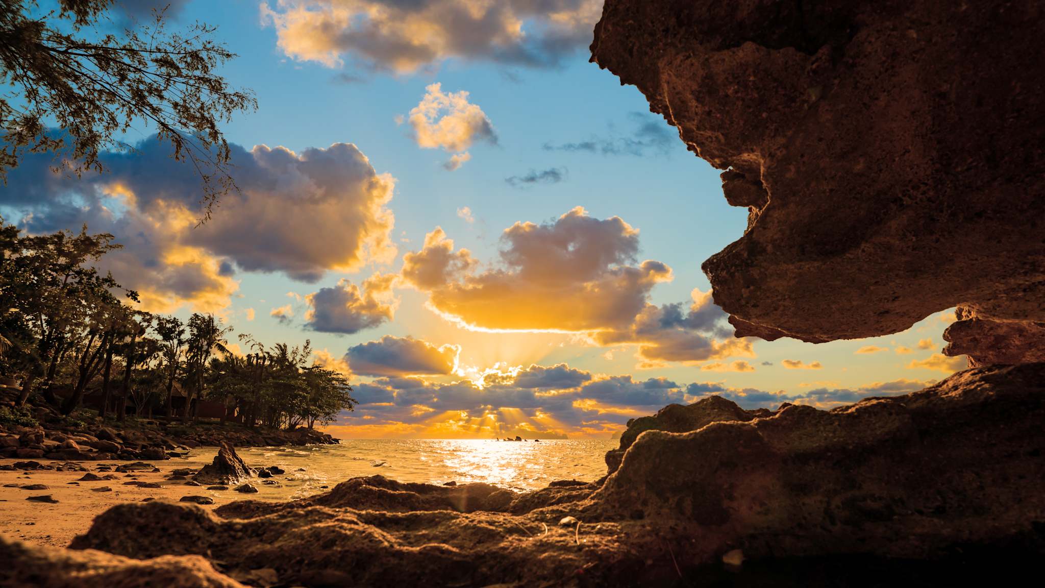 Blick durch Felsen auf einen Strand mit Palmen